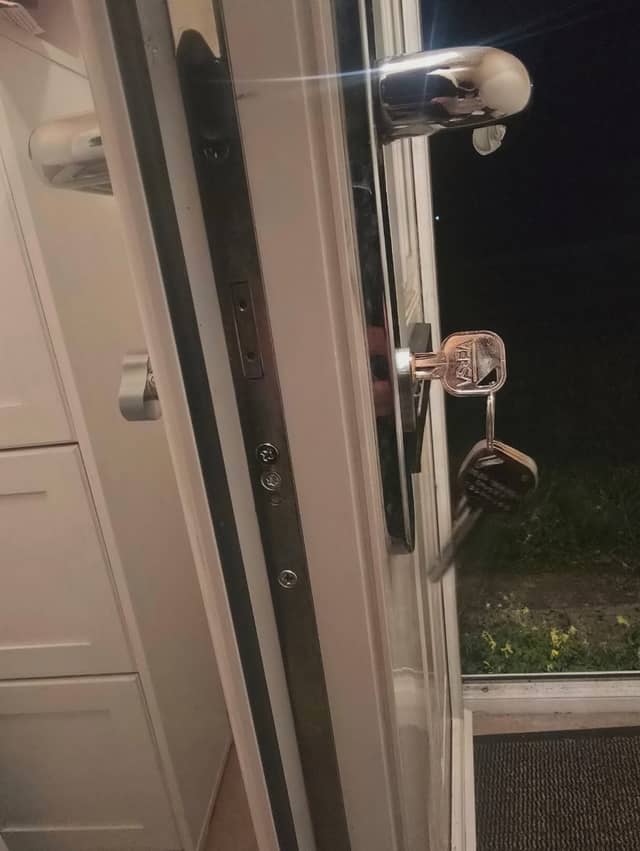 Key in the euro cylinder of a white UPVC front door, multipoint lock strip and handle visible